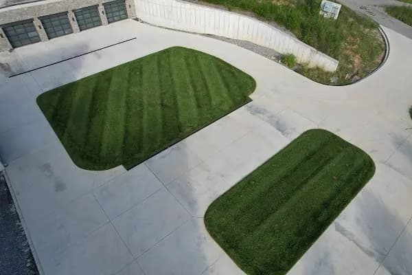 Two striped islands of grass set into a large concrete lot beside a commercial building