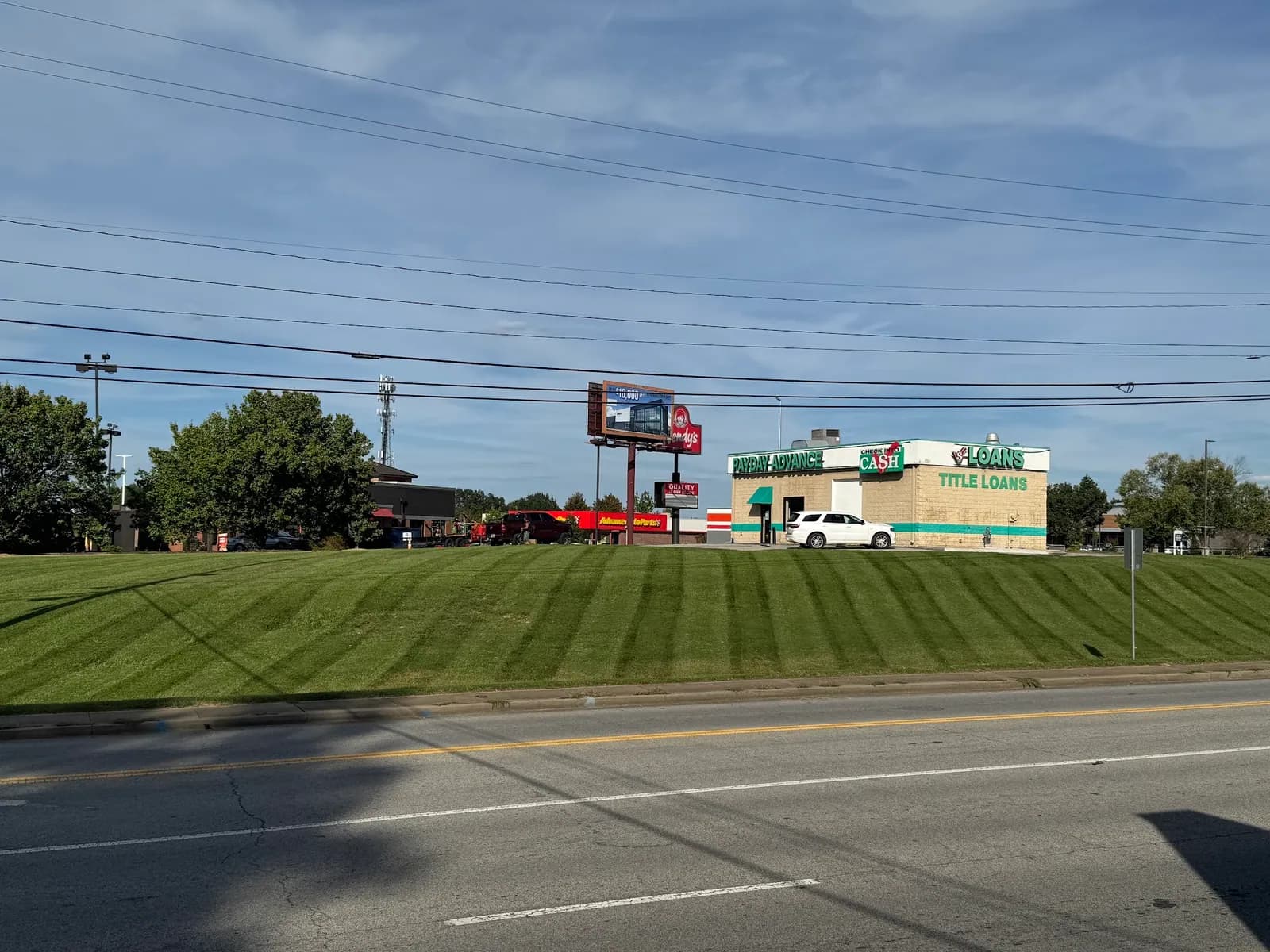 Striped roadside lawn on a commercial lot beside a busy road
